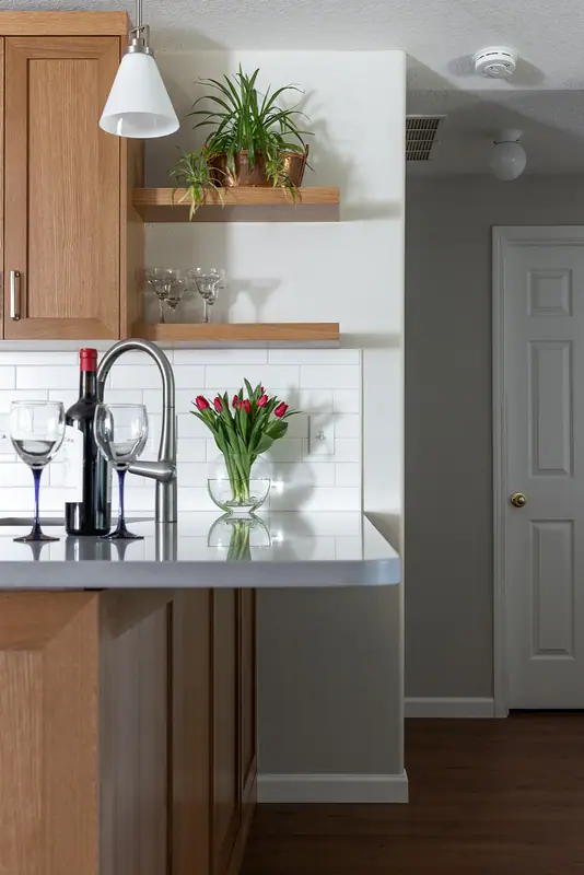 End of the peninsula with faucet, floating shelves and the doorway beyond