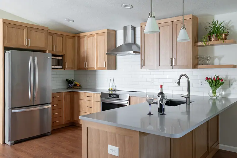 The full L-shaped kitchen with refrigerator, range hood, microwave cabinet and quartz peninsula