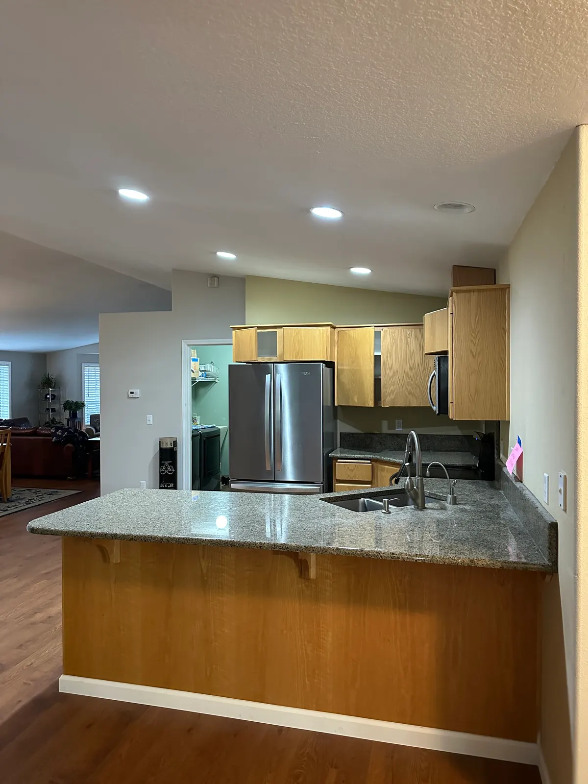 The original Felida kitchen before remodeling, with the sink pushed into the corner of a short angled peninsula and green granite counters