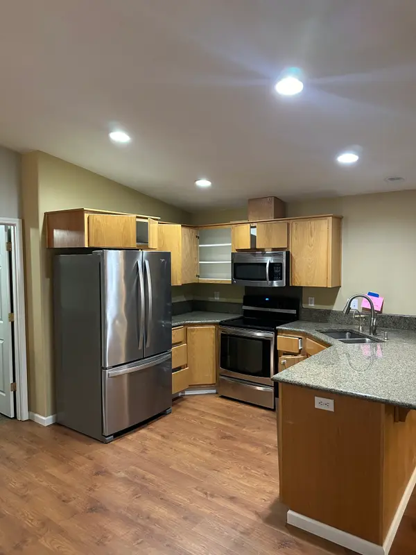 Before the remodel: yellow-toned maple cabinets, green speckled granite and a microwave mounted above the range