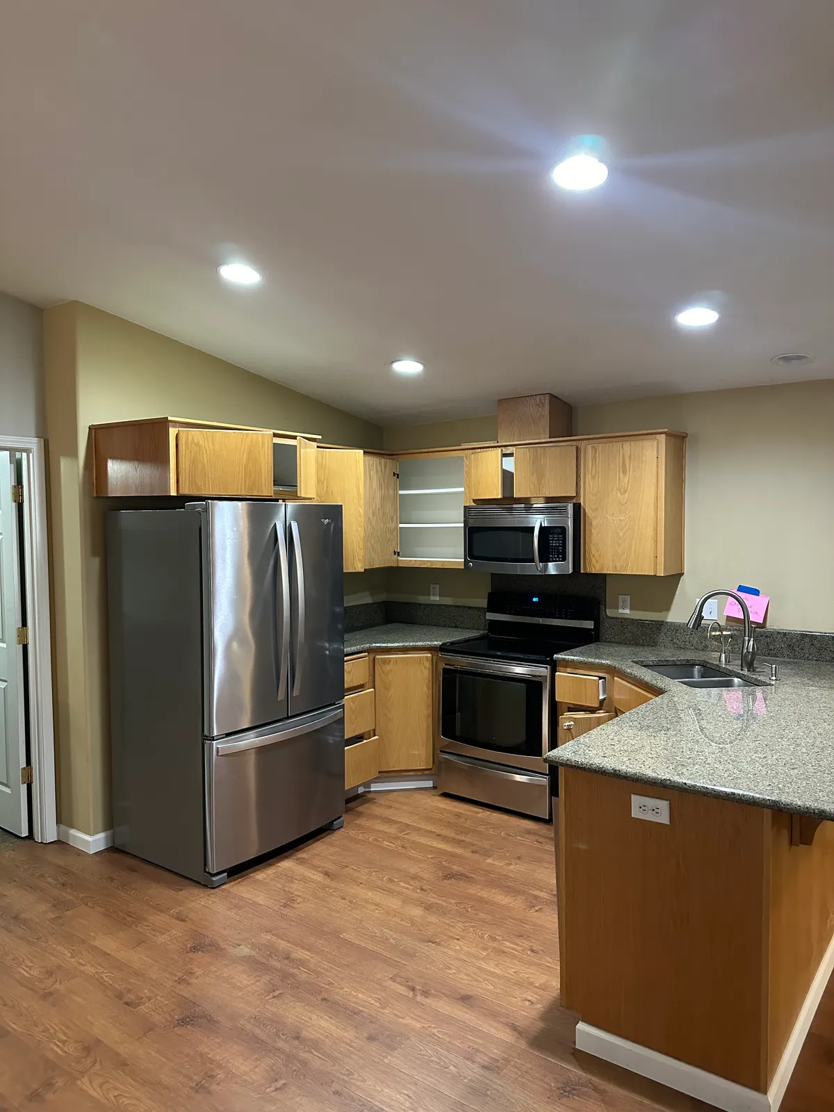 The original kitchen before remodeling, with yellow-toned maple cabinets, green speckled granite and the microwave mounted above the range