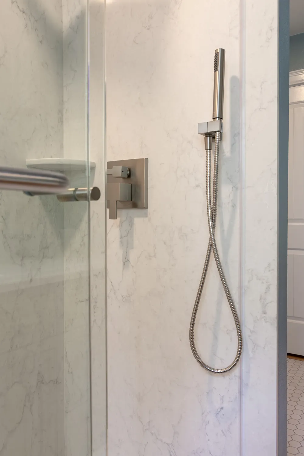 Marble-look shower wall panels with a brushed-nickel handheld shower on a slide bracket and square valve trim