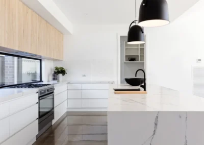 A contemporary kitchen featuring white cabinets and wooden floors, creating a sleek and warm ambiance.