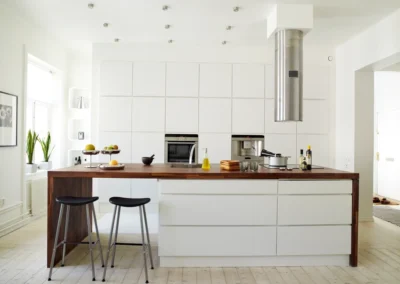 A white kitchen with wooden countertops and stools.