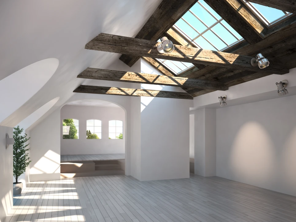 An empty room with a skylight and wooden beams, providing ample natural light and a rustic touch.